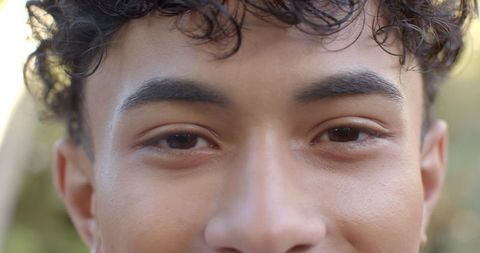 Young Man Gazing with Curly Hair in Sunlit Garden