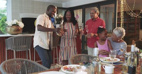 Multigenerational family gathering on patio celebrating with wine, laughter, and shared meal