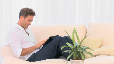 Man Relaxing on Sofa Using Laptop for Leisure Browsing