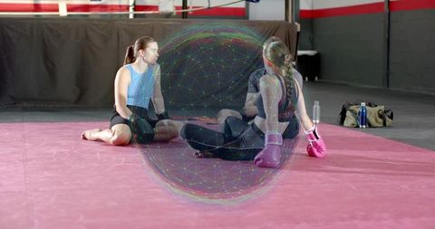 Female fighters sitting on pink mat inside boxing gym wearing pink gloves with network overlay