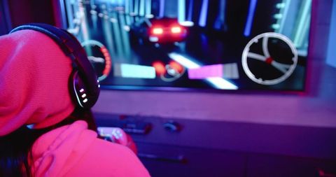 Female gamer holding gamepad playing neon racing on tv in magenta and blue lighting