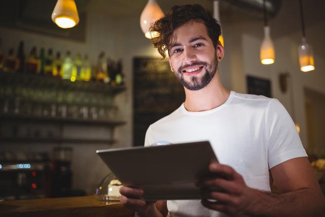 Portrait of smiling man using digital tablet in cafe