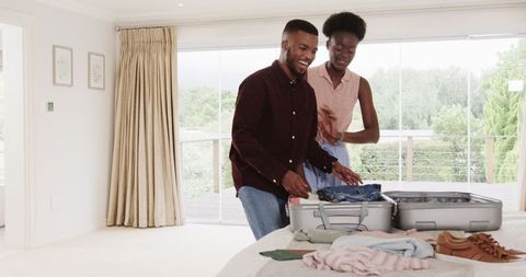 Young couple packing suitcase for vacation at home