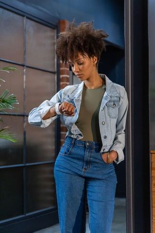 African american professional checking smartwatch in denim jacket in modern loft office