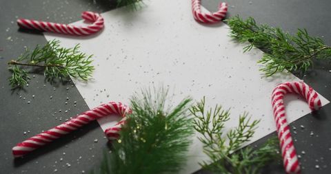 Displaying Blank Holiday Card with Candy Canes and Pine Sprigs on Dark Tabletop