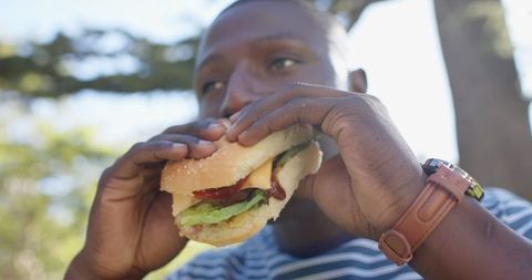 Outdoor hamburger enjoyment in dappled daylight