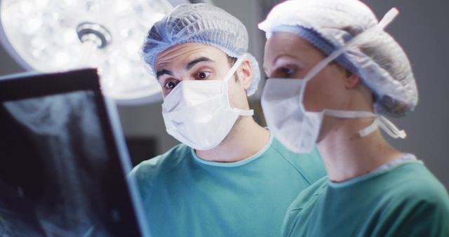 Image of caucasian male and female surgeon studying x-ray in operating theatre. Hospital, medical and healthcare services.