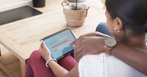 Woman Analyzing Home Energy Usage on Tablet in Living Room