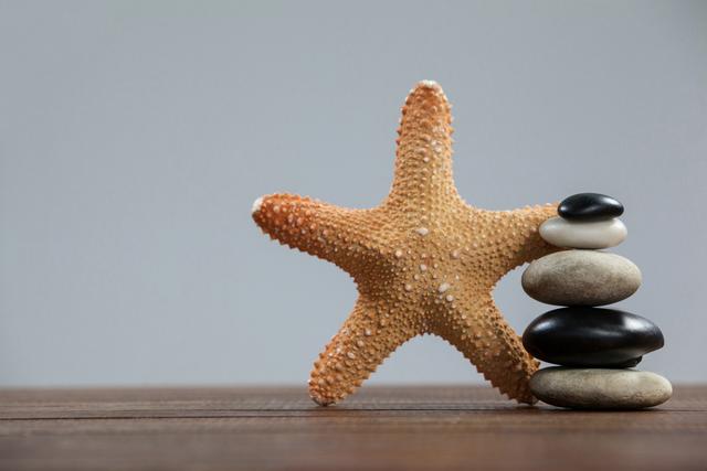 Starfish and Stacked Pebbles on Wooden Surface - Download Free Stock Photos Pikwizard.com