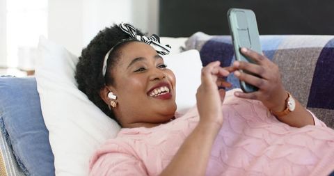 Happy Woman Relaxing on Couch with Phone in Cozy Home Setting