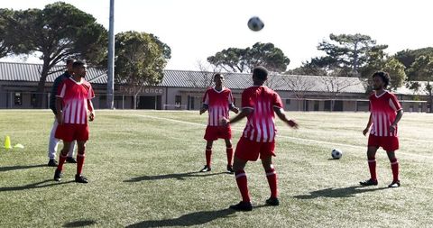 Soccer Players Training on Sunny Field in Red Uniforms