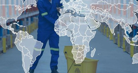 Warehouse janitor mopping industrial aisle with caution bucket and reflective coveralls