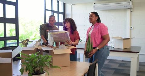 African American Coworkers Unpacking Office Boxes and Inspecting Framed Artwork Together