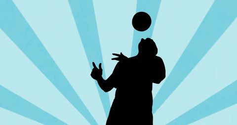 Silhouette of Football Player Juggling Ball Against Dynamic Background