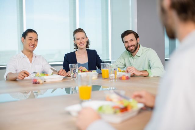 Business executives sitting around a table, enjoying a meal and engaging in conversation. Ideal for use in corporate websites, business presentations, team-building materials, and workplace culture promotions.