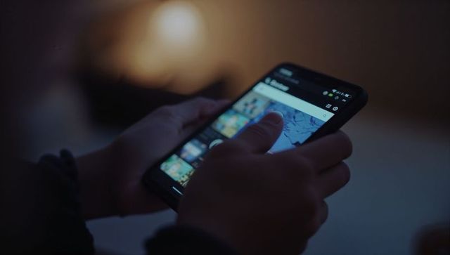 Tapping smartphone gallery in low light at home, browsing photo thumbnails with thumb