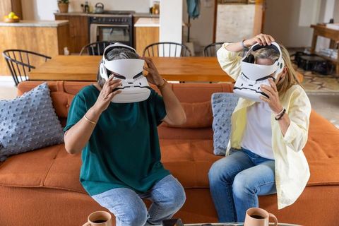 Senior Friends Lifting VR Headsets at Cozy Home