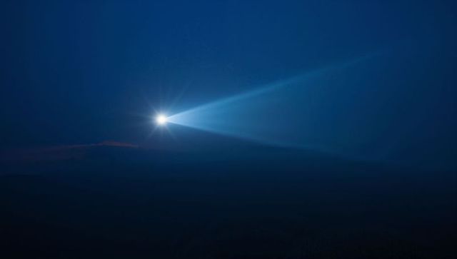 Shining Spotlight Casting Wide Blue Beam Across Misty Night Hills Creating Dramatic Glow
