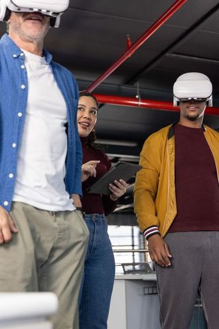 Diverse team wearing vr headsets following tablet guidance in modern collaborative office