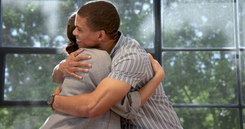 Joyful Businessman Hugging Colleague with Bright Smile