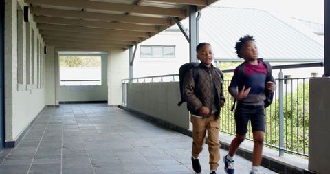 Diverse School Boys Walking in Outdoor Corridor with Backpacks