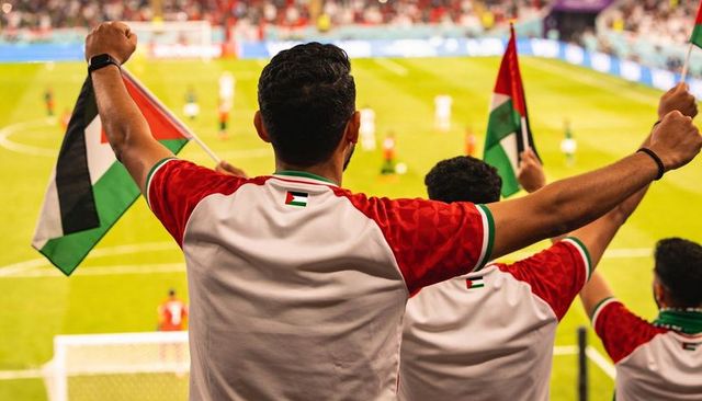 Passionate palestinian fans cheering and waving flags in packed football stadium