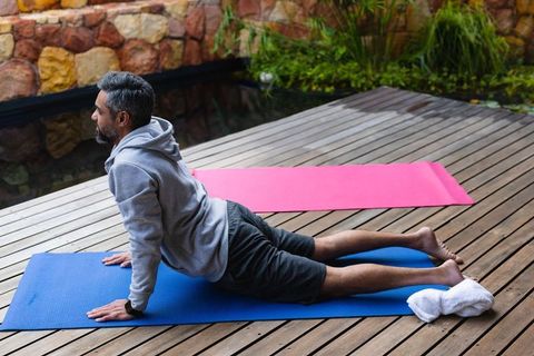 Man Engaging in Outdoor Morning Yoga on a Blue Mat