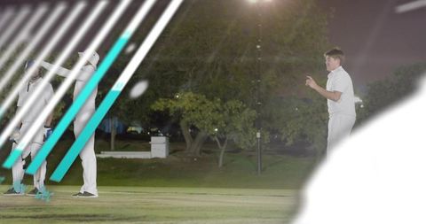 Fast bowler delivering under floodlights on grassy cricket field with teammates