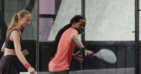 Diverse athletes mastering padel techniques on indoor court