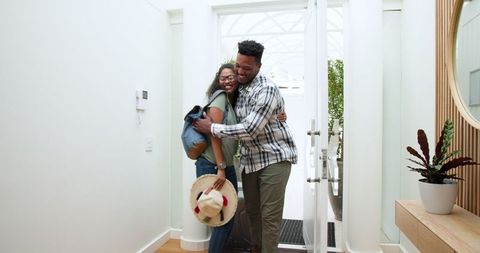 Couple joyfully arriving for vacation embracing in bright hallway
