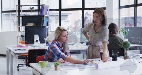 Women Collaborating on Architectural Plans in Open-Plan Office