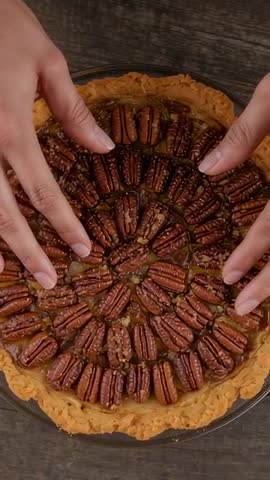 Hands Pressing Pecans into Glossy Caramel Pie, Forming Symmetrical Rings — Vertical Video