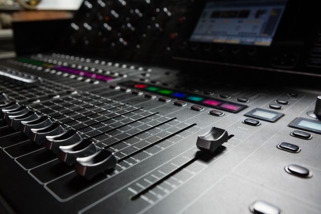 Close-up view of a professional sound mixer with various faders and knobs in a recording studio. Ideal for use in articles, blogs, and websites related to music production, sound engineering, studio equipment, and the recording industry.