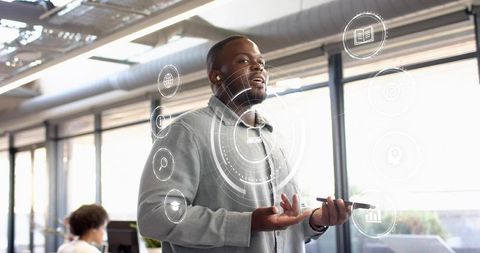 Business presenter using mobile device with augmented HUD overlay in modern open-plan office