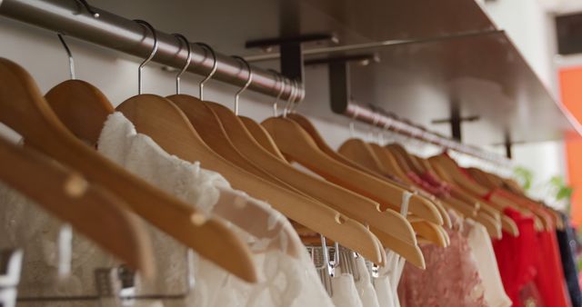 Close up of a line of dresses on clothes hangers displayed hanging on rails in a womens clothing shop, slow motion 