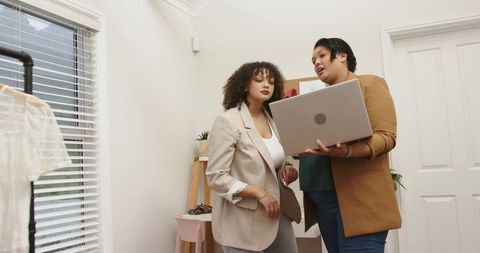 Boutique Stylists Collaborating Over Laptop in Modern Home Fashion Studio