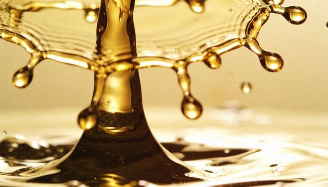 Golden liquid crown splash macro, high-speed droplet collision with reflective ripples