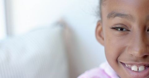 Smiling african american girl closeup on striped couch near window natural pastel light