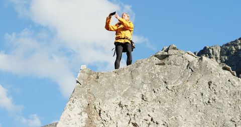 Woman Taking Selfie on Rock Formation Against Blue Sky