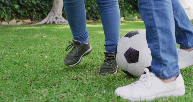 Image of legs of asian mother and daughter playing soccer in garden. Family, motherhood, relations and spending quality time together concept digitally generated image.