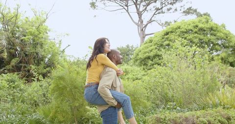 Young Couple Enjoying Piggyback Ride in Lush Green Park