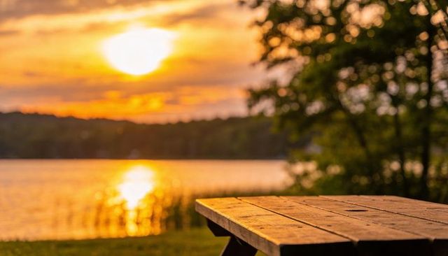 Glowing wooden picnic table at lakeside sunset reflecting golden light