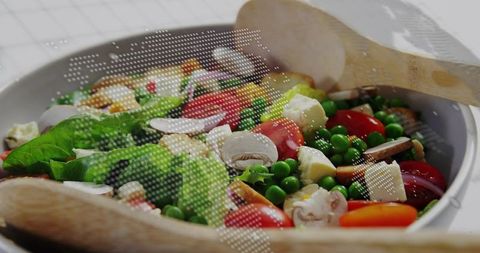 Serving fresh garden salad with cherry tomatoes peas mushrooms feta in white ceramic bowl