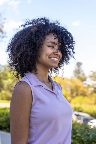 African american woman smiling and enjoying sunny outdoors while wearing lavender polo