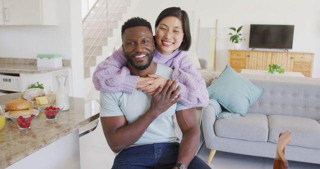 Portrait of happy diverse couple embracing in living room. Spending quality time at home concept.