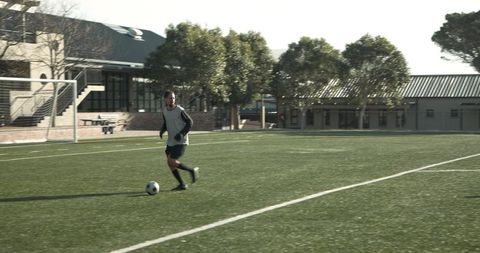 Young Soccer Player Dribbling Ball on Sunny Football Field