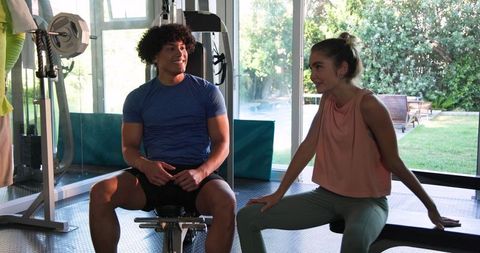 Young couple stretching at gym with fitness instructor guidance
