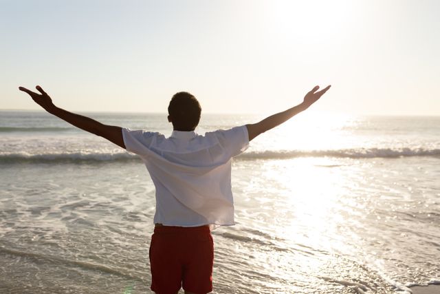 Man standing with arms outstretched on the beach - Download Free Stock Photos Pikwizard.com