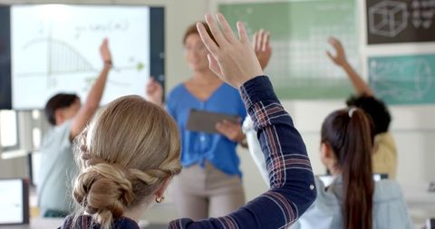 Students Engaged in Learning Environment with Raised Hands
