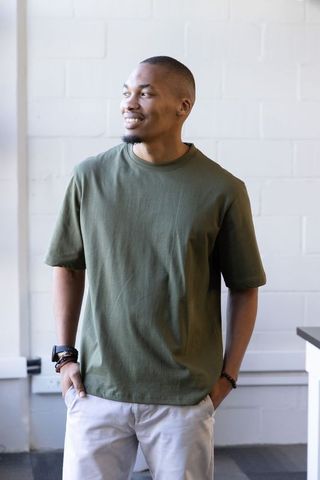 African-american man standing smiling looking left in olive t-shirt casual portrait